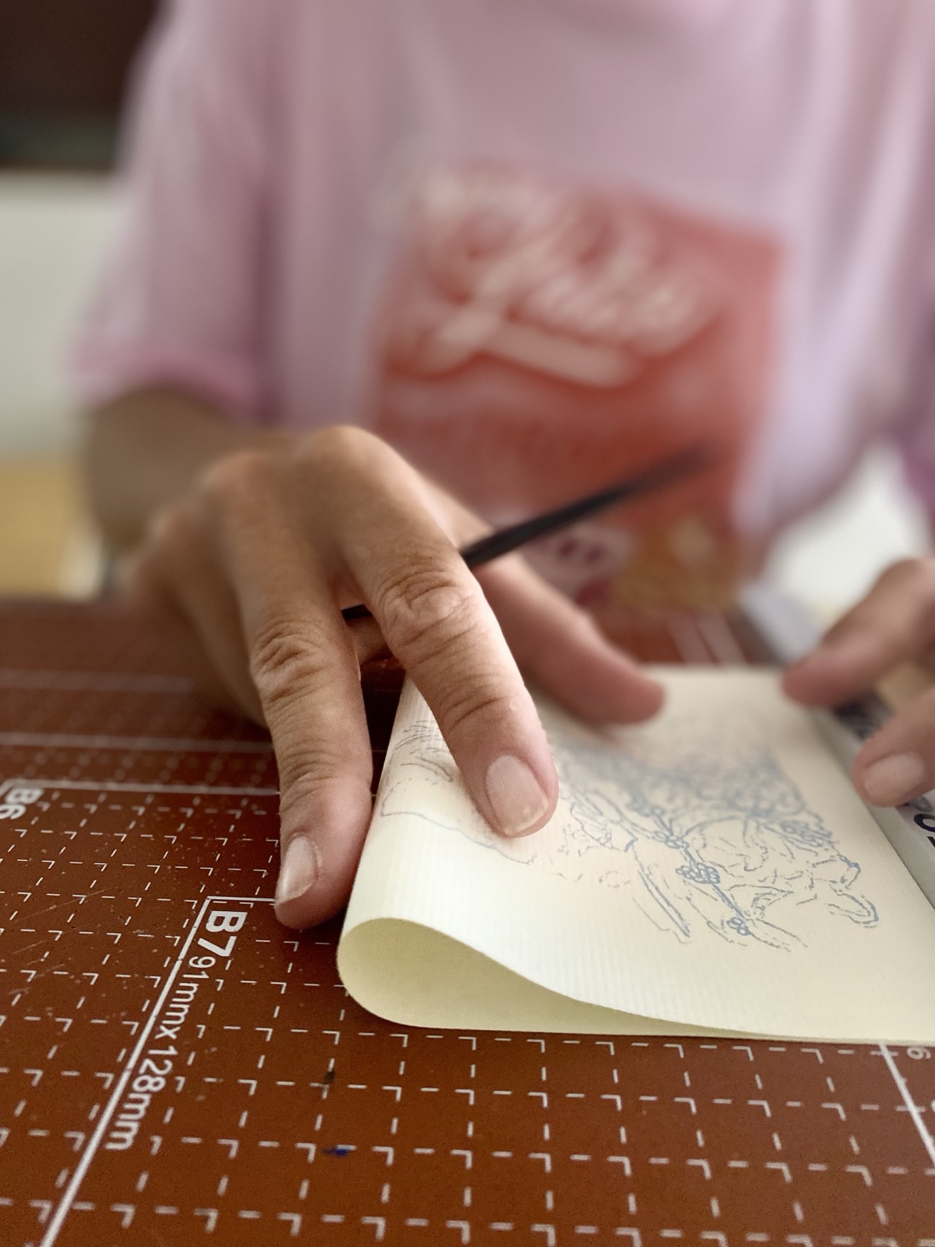 Hands drawing inside a small handmade notebook.
