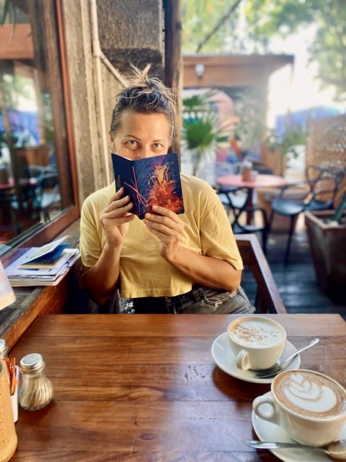 Amandine holding a small notebook in a cafe.
