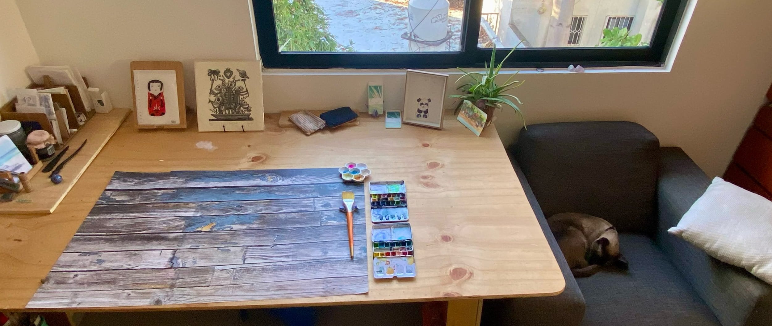 Amandine working at a large studio table surrounded by drawings and materials.